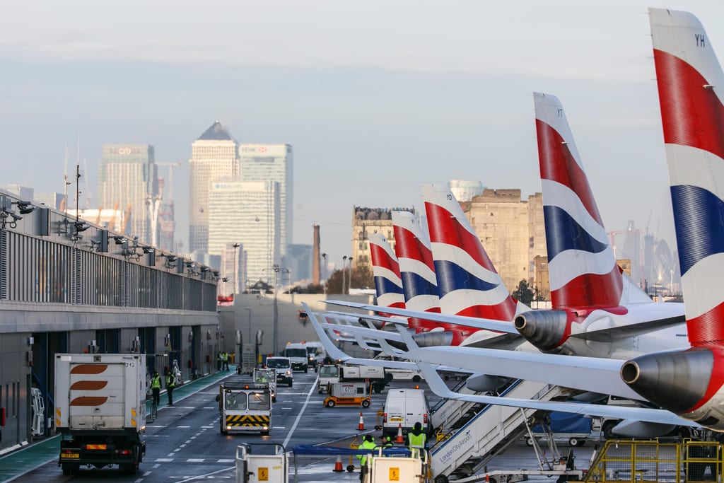 Aircraft tails and apron at London City Airport with the London skyline beyond